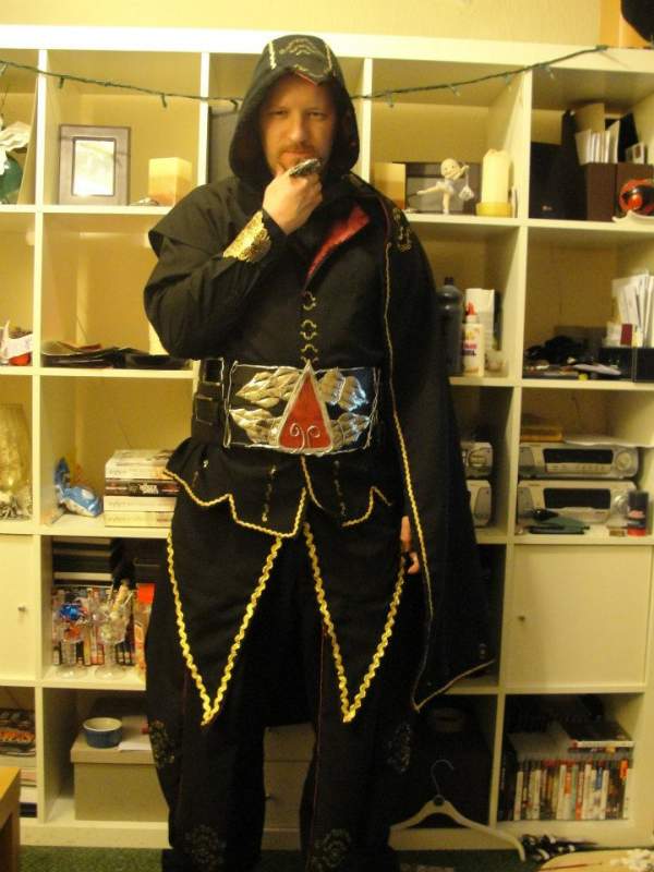 Front view.
Beaked Hood, shirt with red stripe sleeves, Cape w/fur trim, Gold bracer, Lined waiscoat Jacket (No sleeves), Various other flowing compo